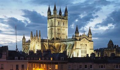 Bath Abbey behind roofs of houses in twilight sky