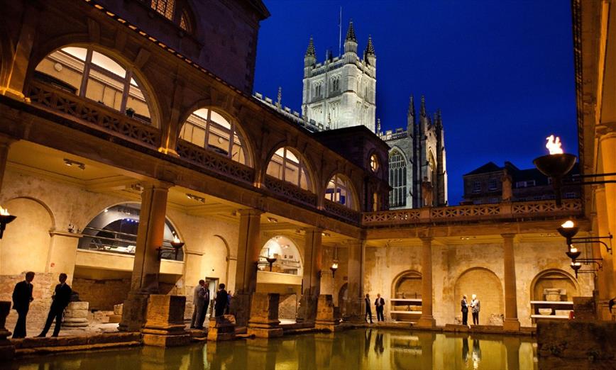 The Roman Baths at night with people enjoying the attraction