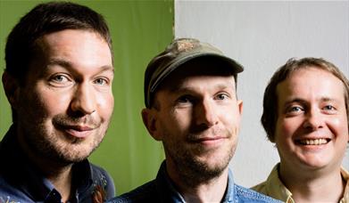 Three men posing for a photograph against a green and white backdrop