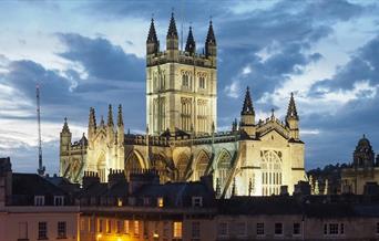 Bath Abbey behind roofs of houses in twilight sky