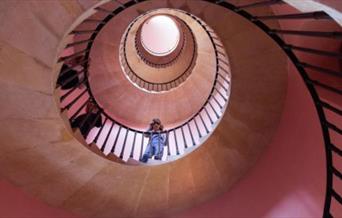 Photo of girl looking down at the camera from a spiral staircase
