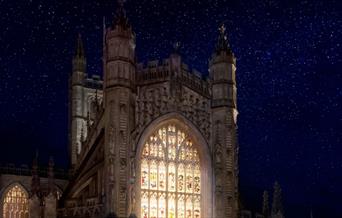 Bath Abbey lit up from inside with stars behind