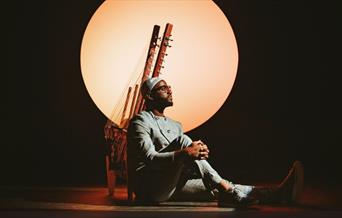 Seckou Keita sat with his instrument in front of the setting sun