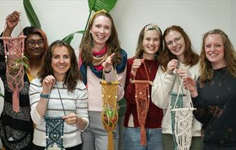 A group of people holding macrame plant hangers