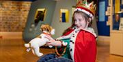 Girl dressed up in royal clothing with toy puppy