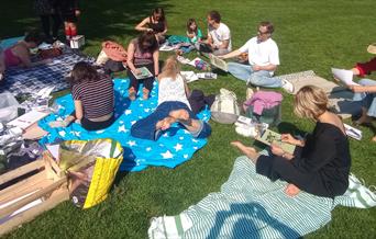 A group of people sitting on a field on picnic blankets