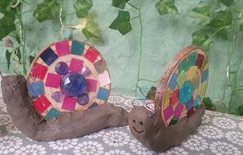 Two model snails made from clay and mosaics