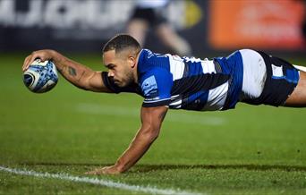 Ollie Lawrence of Bath Rugby extends his arm as he places the ball over the try line.