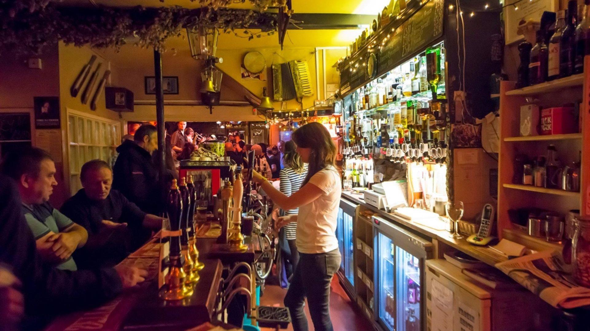 Person pouring drinks in pub