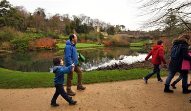 Family walking along a garden path by a pool