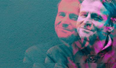 A man grins, there is a pink/futuristic filter. 
