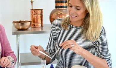 A woman uses a pipette to put fragrance on a scent tester stick