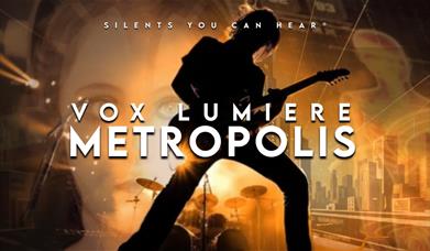 Vox Lumiere Metropolis poster with guitarist silhouette against glowing city backdrop.