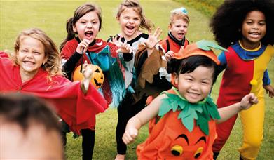 Group of children in Halloween costumes running outside