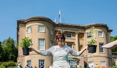 Woman holding plants outside manor house
