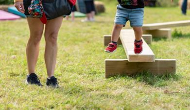 A family playing on balance beams at a National Trust Summer of Play event. Image credit: National Trust Images/Paul Harris