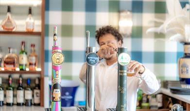 Image of person pouring a pint behind the bar