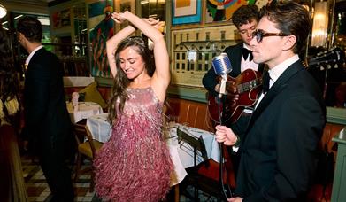 A lady in a pink 1930s style dress dancing to a live performance at The Ivy