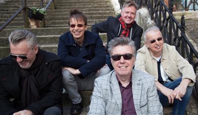 A group shot of The Undertones, all sitting on some steps, looking directly to camera