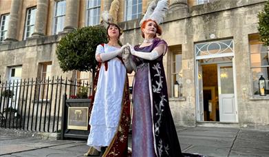 2 women dressed in Regency wear stood outside the Royal Crescent Hotel 