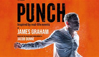 A man stands in front of an orange background, being punched in the face. 