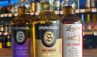 A trio of bottles of Springbank whiskies on a bar counter. 