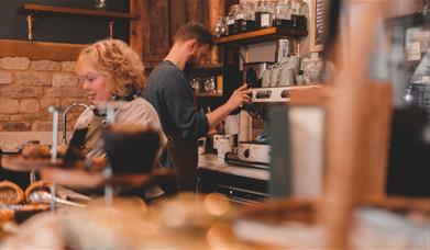 Two baristas serving customers behind the bar at Iford Manor Cafe