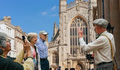 Tour guide discussing Bath Abbey in front of it with the tour group