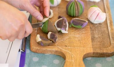 A hand cutting a sweet in half with a knife 