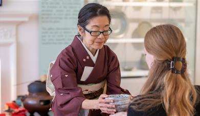 A woman holding a bowl in front of another woman