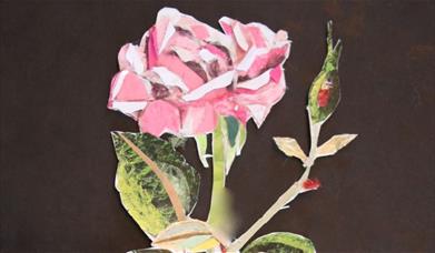 A paper artwork of a rose cut out and glued to a black piece of paper 
