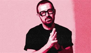 DJ Judge Jules stands with his hands together in front of his chest