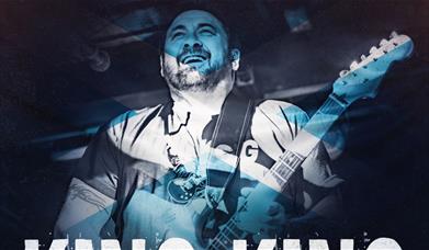 A blue-tinged image of a man playing a guitar