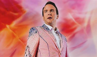 Matt Forde in a glitter suit looking up in awe