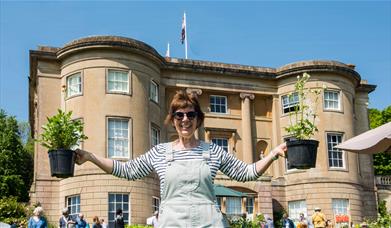 Woman holding plants in front of a Georgian Manor House