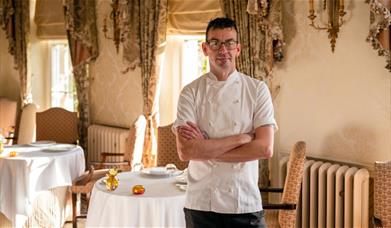 A man wearing a chef's uniform with his arms folded at the Restaurant Hywel Jones in Lucknam Park, near Bath