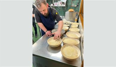 A man kneading dough in a bowl on a kitchen worktop 