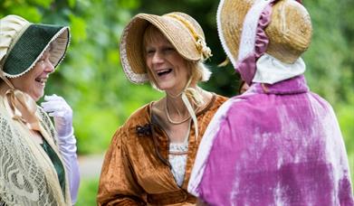 Three women dressed in Jane Austen attire.