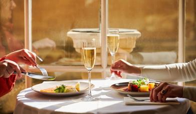 An image of two friends enjoying a delicious evening meal in the sunlit Pump Room