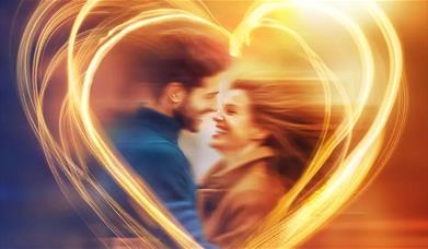 A man and woman embrace each other under a heart shaped silhouette. 