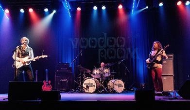 A photo of a rock band playing live on a stage 
