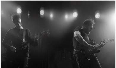 A black and white image of the duo Ben Ottewell & Ian Ball playing guitars on the stage 