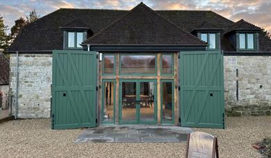 A picture of the front of witchmark distillery with its double green doors on a historic stone barn.