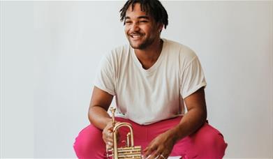 A man smiling while sitting holding a trumpet