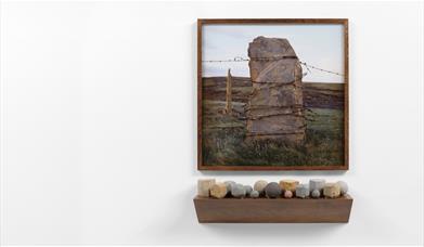 A large standing stone in landscape with barbed wire wrapped around it