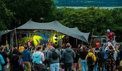 People stood in a field with a stage in the backgroun