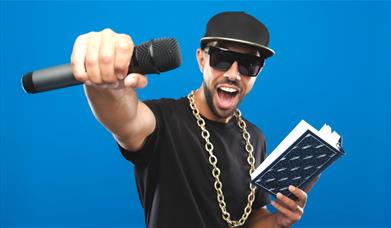 MC Grammar holding a book in one hand and a microphone in the other