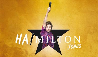 Milton Jones jumping out of a star shape holding up a microhpone