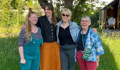 Four women smiling with their arms around each other