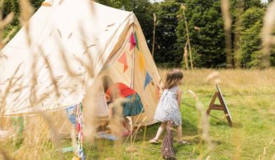 Children playing in the dress up tent in Lacock Abbey's parkland.